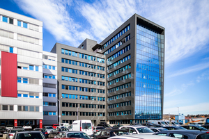  Der zehngeschossige Neubau (hier: Süd-West-Ansicht) grenzt an ein Bestandsgebäude, mit dem die Fassade in Glas und Anthrazit optisch sehr gut harmoniert. 