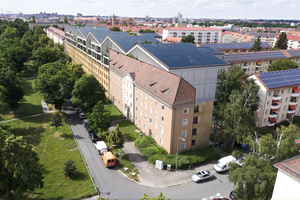  Das Wohngebäude der staatlichen Wohnungsbaugesellschaft Siedlungswerke Nürnberg (linke Bildhäfte) im Stadtteil Ludwigsfeld bildet die Ausgangslage für ein Entwurfs- und Energiekonzept samt urbanen Kontext. Das Rendering (rechts) zeigt das Gebäude nach der Sanierung inkl. der zweigeschossigen Aufstockung in Holzmodulbauweise.  