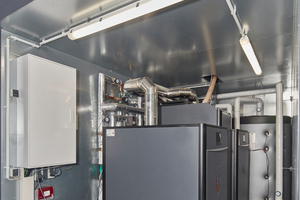  Blick in den Container, Teil 1 der Heizzentrale: Zwei Pelletskessel à 45 kW Leistung, die in bestimmten Phasen im Jahr die Wärmeversorgung anteilig oder ganz übernehmen. Im Hintergrund ist einer von zwei Pufferspeichern zu sehen, die jeweils 1.500 l Warmwasser fassen. 