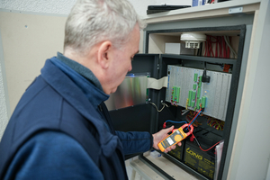  TÜV Süd-Sachverständiger prüft die Brandmelderzentrale auf Alarm- und Ruhestrom, um sicherzustellen, dass die Batterien bei Stromausfall die Funktionsfähigkeit der Anlage gewährleisten. Studien zeigen, dass gerade bei der Energieversorgung oft Mängel bestehen. 