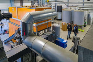  Beeindruckende Dimensionen des zentralen Biomasseheizkessels, auch im Personenvergleich daneben. Der eingesetzte Kessel arbeitet modulierend mit Vorschubrostbetrieb im Leistungsbereich von 270 bis 800 kW und erzeugt jährlich zwischen 2.000 bis 2.500 MWh Wärmeenergie. 