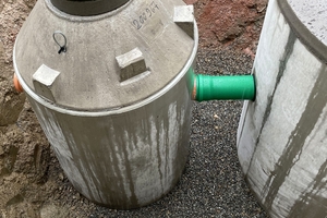  Versetzen der Regenspeicherbehälter unter dem Vorplatz der Carderie. Die im Herstellerwerk komplett vorgefertigten Betonbehälter werden lose auf eine Bettung aus Feinkies oder Splitt gesetzt. Links im Bild der kleinere Filterschacht. Abdeckungen der Belastungsklasse D 400 machen die Behälter LKW-befahrbar. 