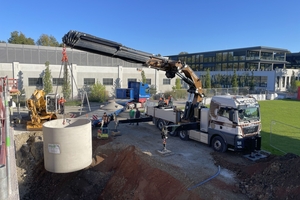  Versetzen der Regenspeicher vom Kran des Lieferfahrzeugs in die vorbereitete Baugrube. Fünf Betonbehälter, die untereinander verbunden sind, bilden die so genannte Mehrbehälteranlage, der ein Filterschacht vorgeschaltet wurde. Dieser reinigt das vom Dach kommende Regenwasser. 