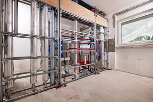  Blick von der Seite der künftigen Küche auf die Trennwand: Oben sind die Befestigungen für die für Hängeschränke, links die Steigleitungen.  