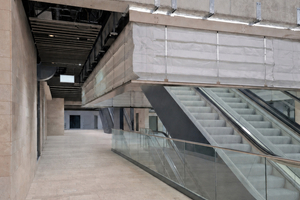  Der abgebildete Verkehrsbereich von Terminal 3 am Flughafen Frankfurt mit Fahrtreppe und offenen Übergängen zeigt, wie die textilen Rauch- und Brandschutzlösungen, darunter gefaltete Rauchschürzen, sich im Bauwerk integrieren. 