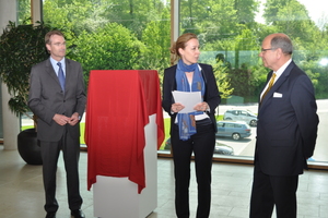  Dr. Christine Lemaitre, Geschäftsführender Vorstand der Deutschen Gesellschaft für nachhaltiges Bauen (DGNB), überreicht die Urkunde zur Platin-Zertifizierung an Dr. Ulrich Stiebel (rechts) und Geschäftsführer Karlheinz Reitze. Unter dem Tuch wartet das Siegel als Plakette auf seine feierliche Enthüllung. 