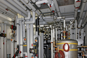  Technikraumim Erdgeschoss, in dem alle Wasserleitungen (warm und kalt) in zwei Behälter zusammengeführt werden; von den sieben Heiz-Wärmepumpen, dem Eislatentspeicher, der Betonkernaktivierung und den Labor-Prüfständen 