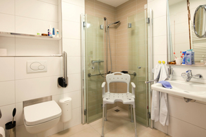  Durch die Installation von bodengleichen Duschen können auch Patienten mit Handicap selbstständig die Duschen nutzen. Als Duschabtrennung wurden Falttüren der Serie „Koralle S500“ gewählt, deren hochtransparente Optik Leichtigkeit sowie Eleganz ausstrahlt 